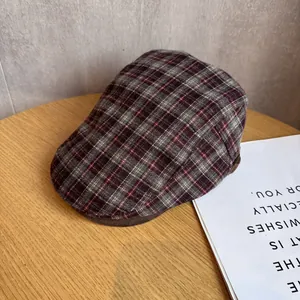Detail view of red and black plaid newsboy cap on a wooden table with soft lighting