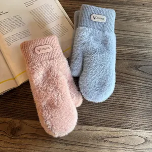 Detail of plush winter mittens featuring knit wrists and a decorative deer head label