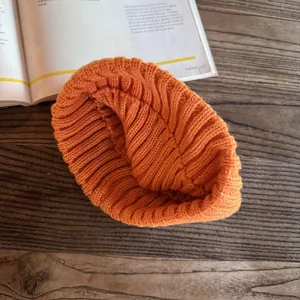 Detailed view of bright orange chunky knit headband on a rustic wooden surface