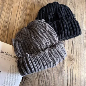 Détails des bonnets en tricot noir et gris avec textures vintage déchirées sur bois