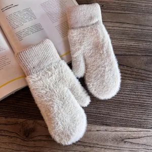 Close-up of beige plush mittens on a wooden table with soft texture and ribbed cuffs