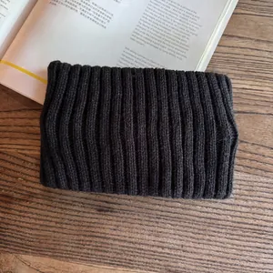 Close-up of solid black ribbed knit headband on vintage wood and book background