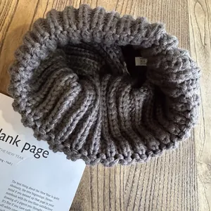 Bonnet en maille gris foncé en acrylique de qualité sur une surface en bois rustique