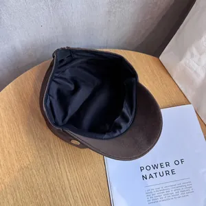 Close-up of dark brown suede equestrian hat with a gold metal emblem on wooden desk