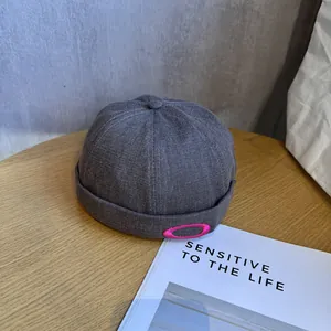 Gros plan du bonnet docker gris foncé avec texture à chevrons et logo brodé rouge