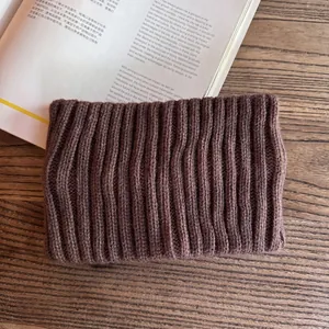 Macro detail of dark brown ribbed knit headband on a wooden background with magazine