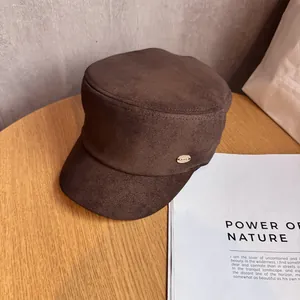 Close-up of a dark brown suede equestrian hat with a golden metallic logo on a wooden table