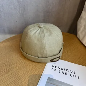 Détail du bonnet docker beige avec motif à chevrons et écusson logo sur une table en bois