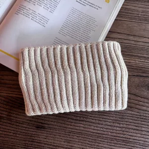 Close-up of beige ribbed knit headband texture on a dark wood table with a magazine