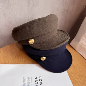 Detail of wool newsboy caps in brown and navy with textured gold metal buttons