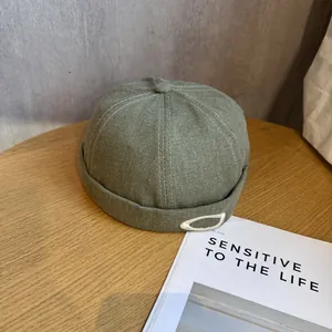 Gros plan du bonnet miki olive avec texture en sergé et broderie blanche sur bois