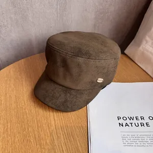 Detail of dark brown suede equestrian hat with a gold metal Riod plaque on a wooden table