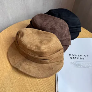 Detail of vintage suede baker boy hats in brown and black on a wooden background