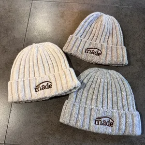 Trois bonnets en maille avec broderie 'made' en beige, marron clair et gris élégant