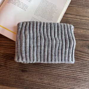 Detail of grey knitted headband showing vertical ribbed texture on a wooden desk