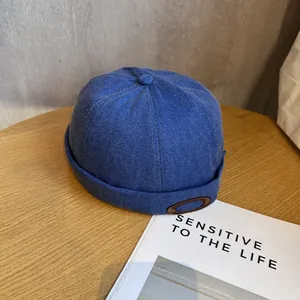 Détail du bonnet docker bleu marine à texture sergé et écusson en cuir marron vintage