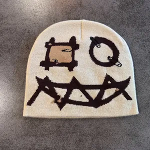 Detailaufnahme der cremefarbenen Strickmütze mit braunen geometrischen Mustern