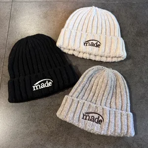 Détails de la maille côtelée et broderie 'made' sur les bonnets d'hiver