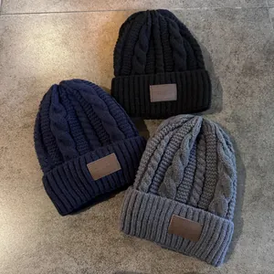 Detail van kabelgebreide textuur en lederen patches op winterse mutsen voor heren