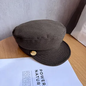 Close-up of textured newsboy hat fabric featuring a decorative gold relief button