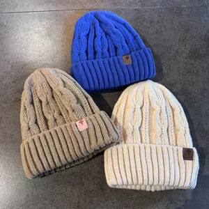 Tre berretti caldi in maglia a trecce blu, kaki e bianco con logo a stella in pelle