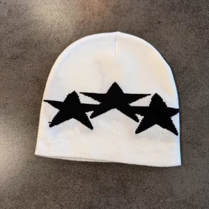 Close-up of white knitted beanie with black star patterns and detailed knit texture