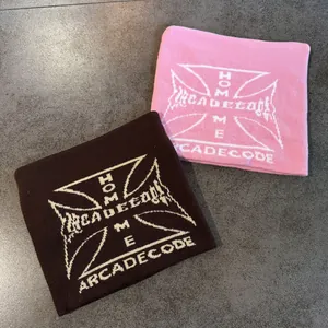 Detailed knit texture of pink and brown beanies featuring white cross and logo embroidery