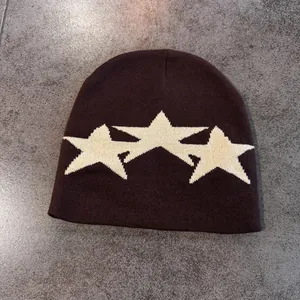 Detailed view of the dark brown knitted beanie featuring white star jacquard patterns