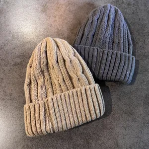 Dettagli della trama a trecce su berretti invernali beige e grigio scuro con risvolto