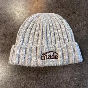 Gros plan détaillé du bonnet en maille côtelée gris clair avec broderie 'made'