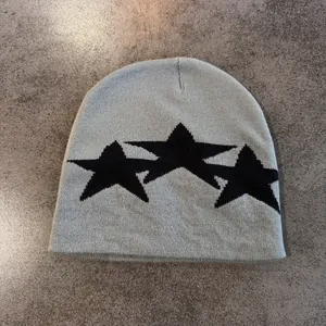 Macro detail of the grey knitted beanie featuring black star embroidery patterns