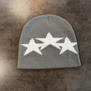 Detailed knit texture of a grey beanie featuring three white star embroidery accents