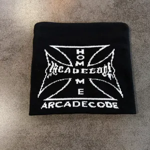 Macro view of black knit beanie featuring white jacquard cross pattern and Home text