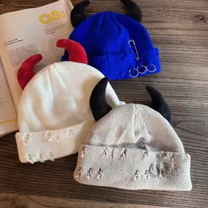 Distressed knit beanies with devil horns, metal safety pins and ring decorations