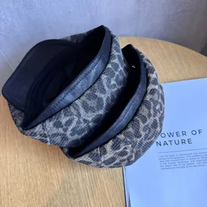 Vintage leopard print beret with leather trim edge displayed on a wooden desk with magazine