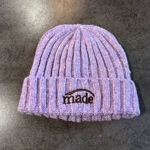 Détail du bonnet en tricot lavande avec broderie marron sur le revers plié