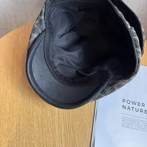 Close-up of leopard print newsboy cap with black leather brim and size label inside