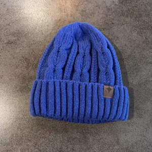 Dettaglio del berretto blu a maglia intrecciata con trama spessa e toppa a stella in pelle