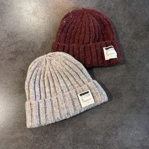Detail of mixed-color knit beanies showing ribbed texture and handmade woven label