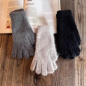 Detail of plush knitted winter gloves in grey, beige and black with ribbed cuffs