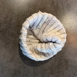 Detail of light beige knitted hat texture with mixed fibers and internal care label