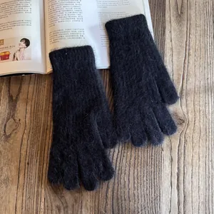 Close-up of soft black plush knit gloves with warm texture on wooden background