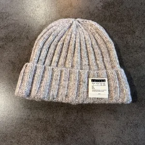 Close-up of a chunky ribbed knit beanie with a folded cuff and woven label detail