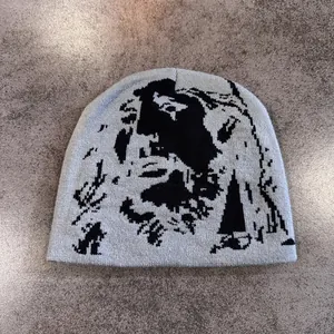Nahaufnahme der hellgrauen Strickmütze mit schwarzem pixeligem Porträtmuster Textur