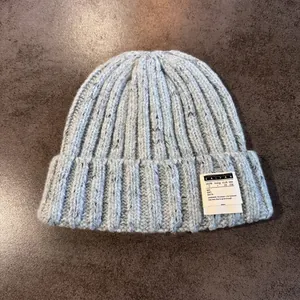 Detailed close-up of light blue knit beanie showing thick ribbed texture and woven label