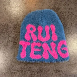 Close-up detail of plush blue faux fur beanie featuring pink knitted RUI TENG lettering