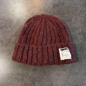 Close-up of deep red knit beanie with vintage flecked texture and woven patch detail