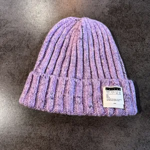 Detail shot of purple chunky knit beanie with colorful speckles and woven brand label
