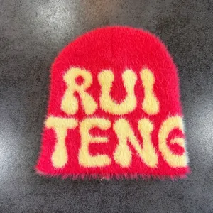 Detail of faux mink fur knit beanie with yellow RUI TENG lettering on rose red texture