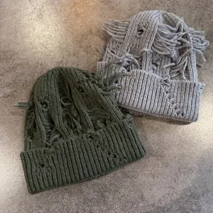 Primer plano de gorros de punto en gris y oliva con detalles de agujeros desgastados